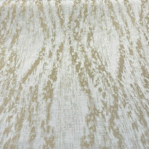 May include: White fabric with a subtle, textured, gold-colored pattern. The pattern resembles a wood grain or a natural, organic design.