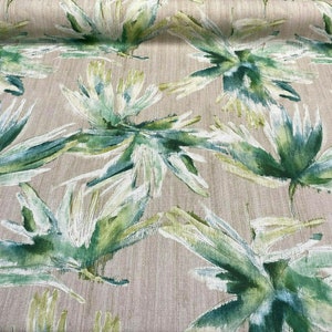 May include: A beige fabric with a green and white watercolor-style leaf pattern. The leaves are stylized and abstract.