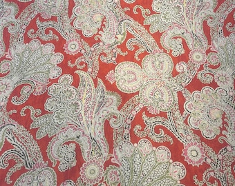 May include: Red fabric with a paisley pattern in shades of green, white, and pink.