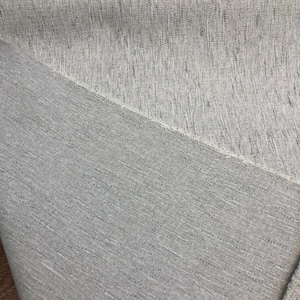 May include: Close-up of a light gray fabric with a subtle textured pattern. The fabric has a slightly rough feel and a woven appearance.