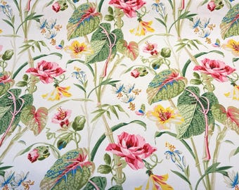 May include: A white fabric with a floral pattern featuring pink, yellow, and green flowers. The flowers are arranged in a repeating pattern on a white background.
