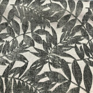 Puede incluir: Primer plano de una tela con un dise&ntilde;o texturizado y en relieve de hojas grises oscuras sobre un fondo gris claro.