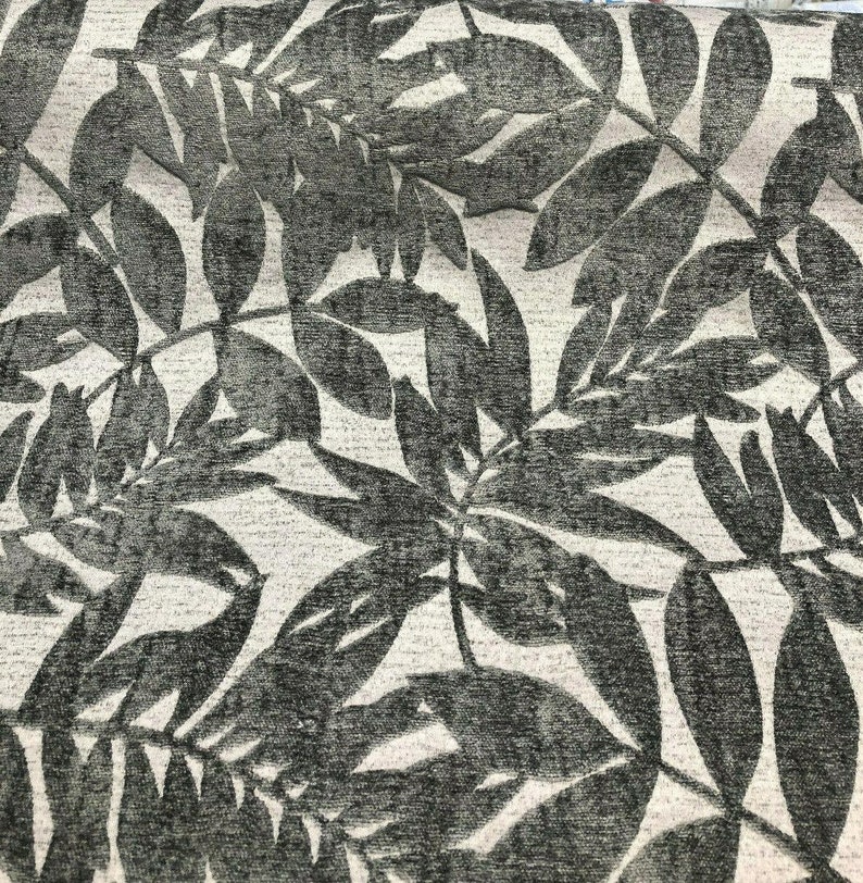 Puede incluir: Primer plano de una tela con un dise&ntilde;o texturizado y en relieve de hojas grises oscuras sobre un fondo gris claro.