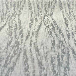May include: A white fabric with a gray abstract pattern. The pattern resembles a wood grain or a natural texture.