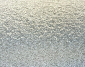 May include: Close-up of a white, textured fabric. The material has a soft, plush appearance with a dense, looped pile. The color is a bright, clean white, suggesting a cozy and inviting texture, suitable for home decor or apparel.