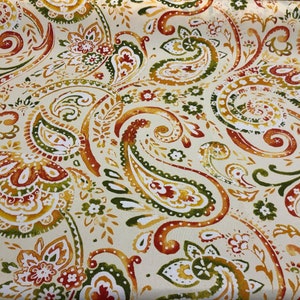 May include: A cream-colored fabric with a paisley pattern in shades of orange, green, and yellow.