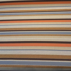Puede incluir: Primer plano de una tela con rayas horizontales en tonos marrones, naranjas y azules. Las rayas son de diferentes anchos e incluyen un detalle de línea punteada. El patrón general es un diseño de rayas repetitivo.