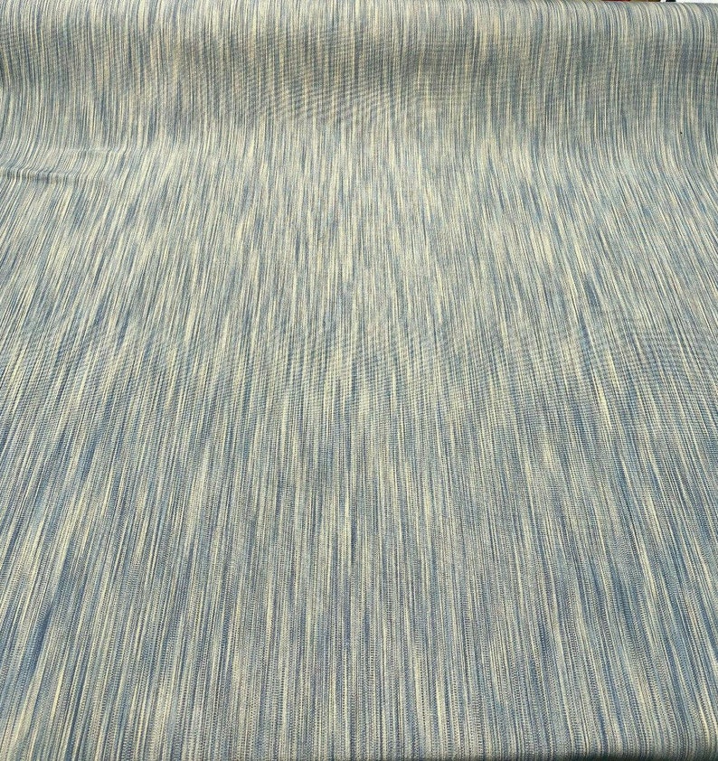 May include: A close-up of a blue and white striped fabric. The fabric has a subtle sheen and a slightly textured surface.