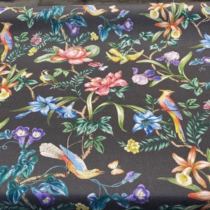 May include: Black fabric with a repeating pattern of colorful flowers, birds, and leaves. The fabric has a dark background with bright colors.