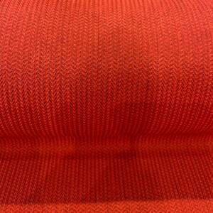 May include: Close-up of a red fabric with a herringbone weave pattern.
