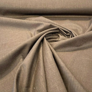 May include: Close-up of a brown fabric with a subtle textured pattern. The fabric is folded and draped, showcasing its soft and smooth texture.