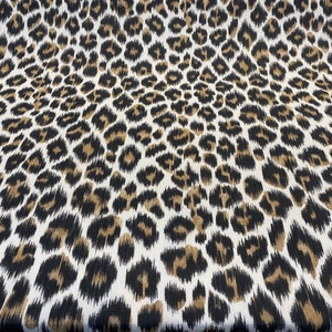May include: White fabric with a brown and black leopard print pattern.