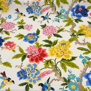 May include: Floral fabric featuring a repeating pattern of large, colorful flowers and birds. The design includes blue, pink, and yellow blossoms with green leaves and brown branches, set against a white background.