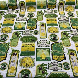 May include: A white fabric with a repeating pattern of green and yellow olive oil labels. The labels feature illustrations of olives, bottles of olive oil, and text in French that reads "huile d'olive" and "produit de provence".