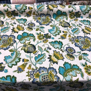 May include: White fabric with a blue, green, and yellow floral pattern. The fabric features a repeating design of stylized flowers and leaves.