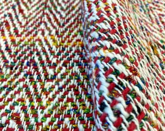 Puede incluir: Primer plano de una tela tejida roja, blanca y verde con un patrón de espiga. La tela es texturizada y tiene un aspecto ligeramente peludo.