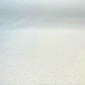 May include: A close-up of a white textured surface. The surface has a slightly grainy texture.