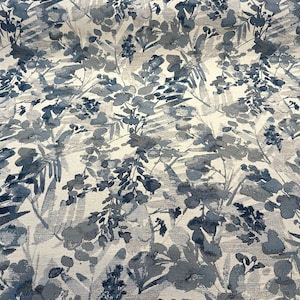 May include: A white fabric with a blue and gray floral pattern. The pattern features abstract leaves and flowers.