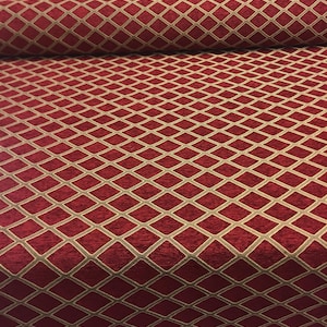 Pode incluir: Tecido de estofamento vermelho com um padrão de diamante na cor dourada.