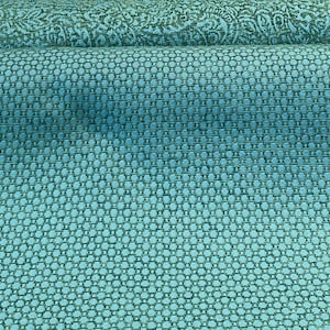 May include: Teal fabric with a small, repeating pattern of circles. The fabric has a subtle sheen and a textured surface.