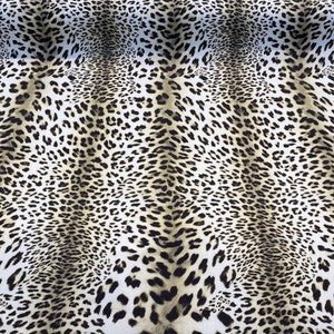 May include: A close-up of a fabric with a brown and white leopard print pattern.