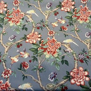 Könnte beinhalten: Ein blauer Stoff mit einem floralen Muster mit rosa und roten Blumen, grünen Blättern und gelben Vögeln. Der Stoff hat ein sich wiederholendes Muster.