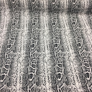 May include: Black and white snake skin patterned fabric. The fabric has a textured surface.
