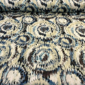 May include: A fabric with a tie-dye pattern in shades of blue, brown, and white. The pattern is made up of circles and swirls.