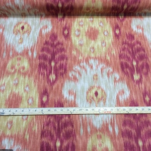 May include: Red, beige, and yellow ikat fabric with a repeating pattern. The fabric is measured with a ruler, showing 30 inches.
