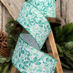 May include: Green and white ribbon with a watercolor leaf pattern. The ribbon is wired and has a green edge.