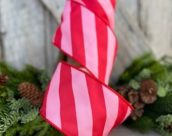 May include: Red and pink striped ribbon with a satin finish. The ribbon is rolled up and ready to be used for crafting or decorating.