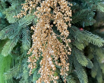 May include: A decorative hanging ornament featuring a cluster of metallic gold berries and thin, branching stems. The ornament has a shimmering, reflective finish and is composed of numerous small, round spheres attached to delicate, twig-like structures.