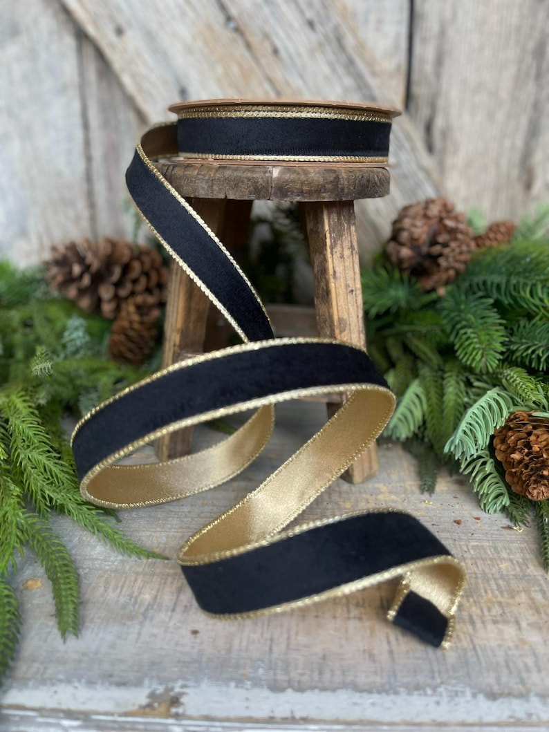 May include: Black velvet ribbon with a gold trim. The ribbon is coiled on a wooden stool.