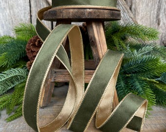 May include: A spool of double-sided ribbon featuring a dark olive green velvet texture on one side and a metallic gold satin finish on the other. The edges of the ribbon are finished with a thin, metallic gold stitched trim along both sides.