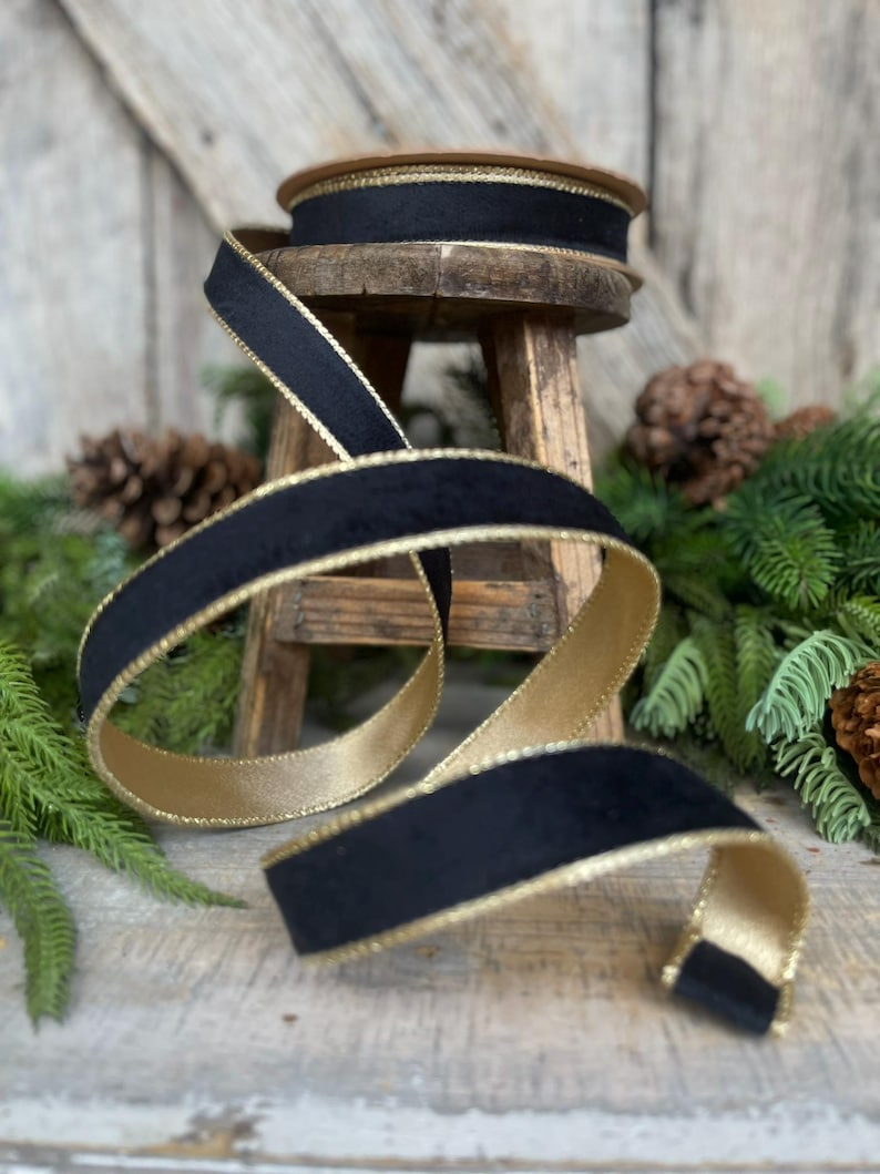 May include: Black velvet ribbon with a gold trim. The ribbon is wrapped around a wooden spool and is sitting on a wooden stool.