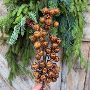 May include: A decorative floral stem featuring numerous round, copper-colored berries with a textured, glittery finish. The berries are clustered along thin, brown branches, creating a dense, spherical arrangement on the main stem.