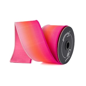 May include: A roll of pink and orange ombre ribbon with a white edge. The ribbon is on a spool with the word "remarkable" printed on it.
