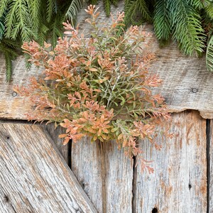 May include: A bundle of artificial greenery with orange and green leaves. The faux plant has a natural appearance and is suitable for home decor or crafting projects. The leaves have a frosted finish, adding a touch of elegance.