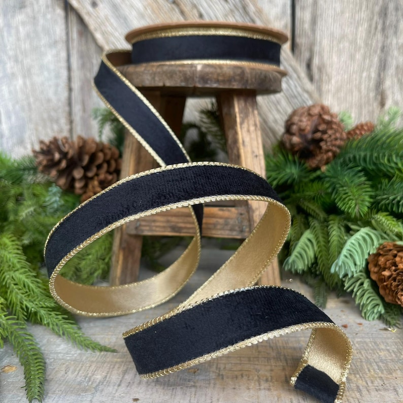 May include: Black velvet ribbon with a gold trim. The ribbon is rolled up on a wooden spool.