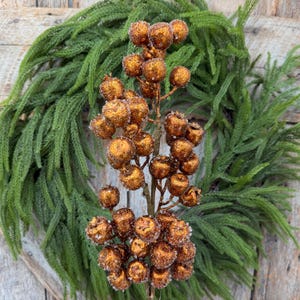 May include: A decorative floral stem featuring numerous round, copper-colored berries with a textured, glittery finish. The berries are clustered along a central brown branch, creating a dense, spherical arrangement of metallic-toned fruit.
