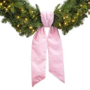 May include: A pink velvet bow for a Christmas garland. The bow is tied in a simple knot and has two long tails.