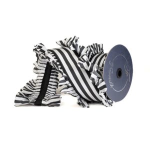 May include: A spool of black and white striped ribbon with ruffled edges. The ribbon is paired with a dark blue spool with the text "Frensilks" and a logo. The ribbon is a decorative craft supply.