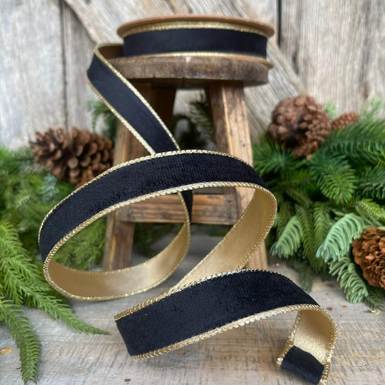 May include: Black velvet ribbon with a gold trim. The ribbon is rolled up and sitting on a wooden stool.