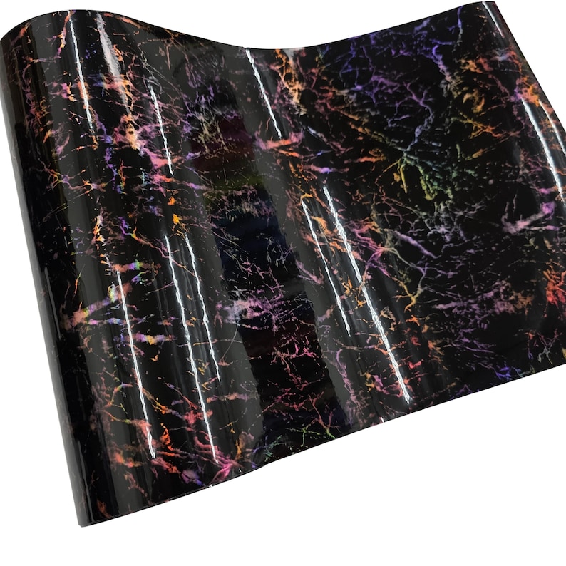 May include: A sheet of glossy black vinyl with a marble-like pattern. The design features streaks of orange, pink, purple, and yellow, creating a colorful, iridescent effect. The material is rolled and ready for use.