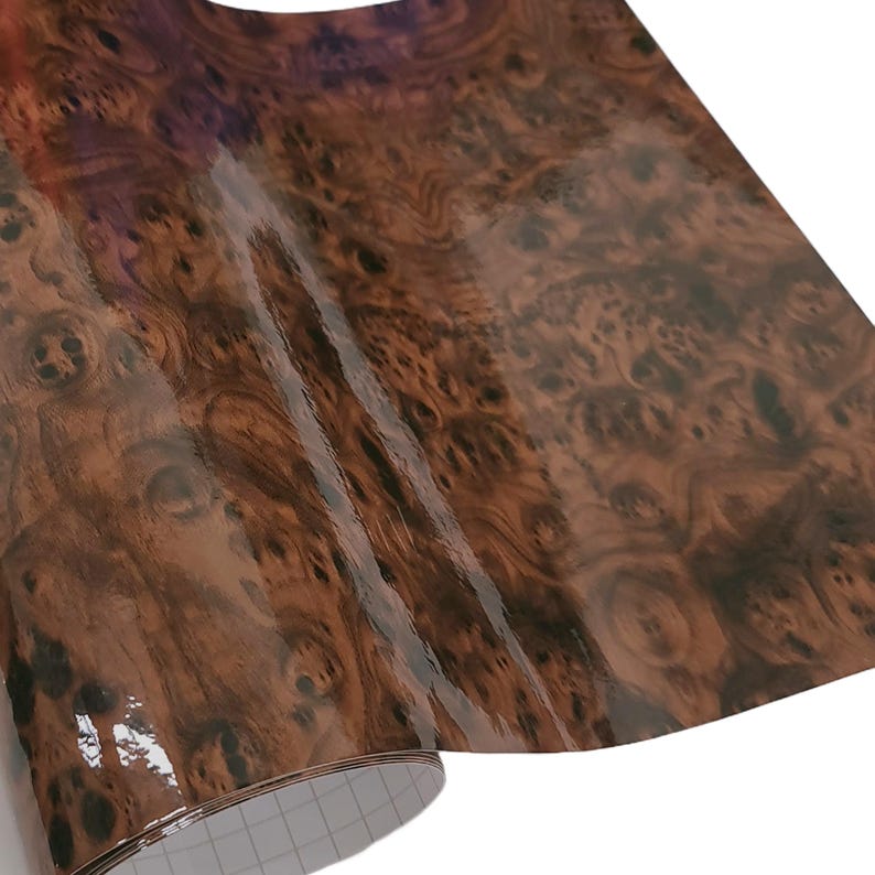 May include: A roll of brown woodgrain vinyl wrap with a glossy finish. The vinyl is rolled up and the end of the roll is visible.