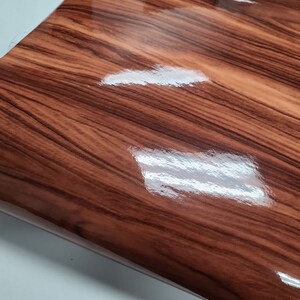 May include: A close-up of a brown woodgrain vinyl sheet with a glossy finish.