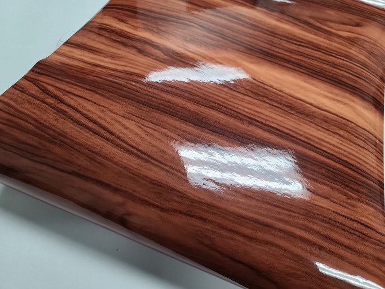 May include: A close-up of a brown woodgrain vinyl sheet with a glossy finish.