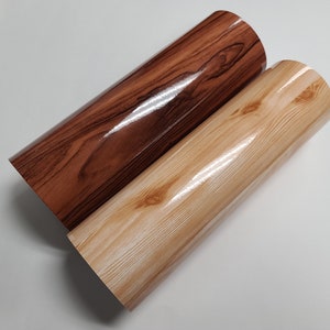 May include: Two rolls of wood-grain vinyl adhesive paper. One roll is brown with a dark wood grain pattern, and the other roll is light brown with a lighter wood grain pattern.