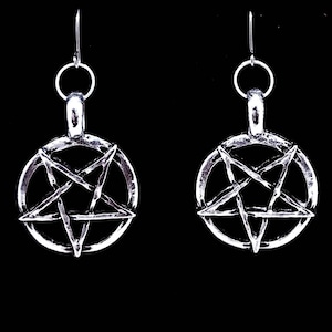 May include: A pair of silver earrings with a pentagram design. The earrings are hanging from silver hooks.