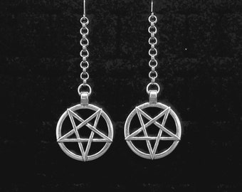 Könnte beinhalten: Ein Paar silberne Ohrringe mit einem Pentagramm-Anhänger an jedem Ohrring. Die Ohrringe befinden sich auf einem schwarzen Hintergrund.